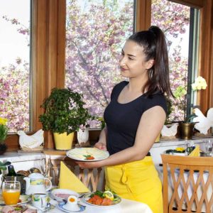 Freundliche Servicekraft serviert Frühstück.